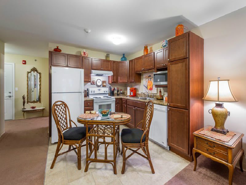A cozy kitchen and dining area with wooden cabinets, a small round table, and wicker chairs.