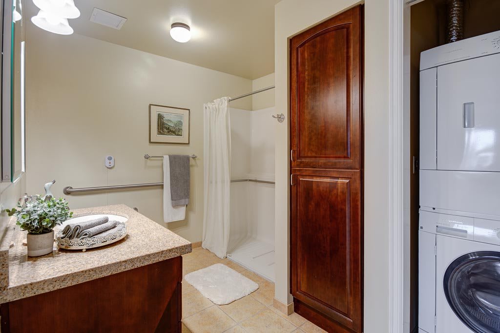 A modern bathroom featuring a shower, wooden cabinet, and neatly arranged towels.