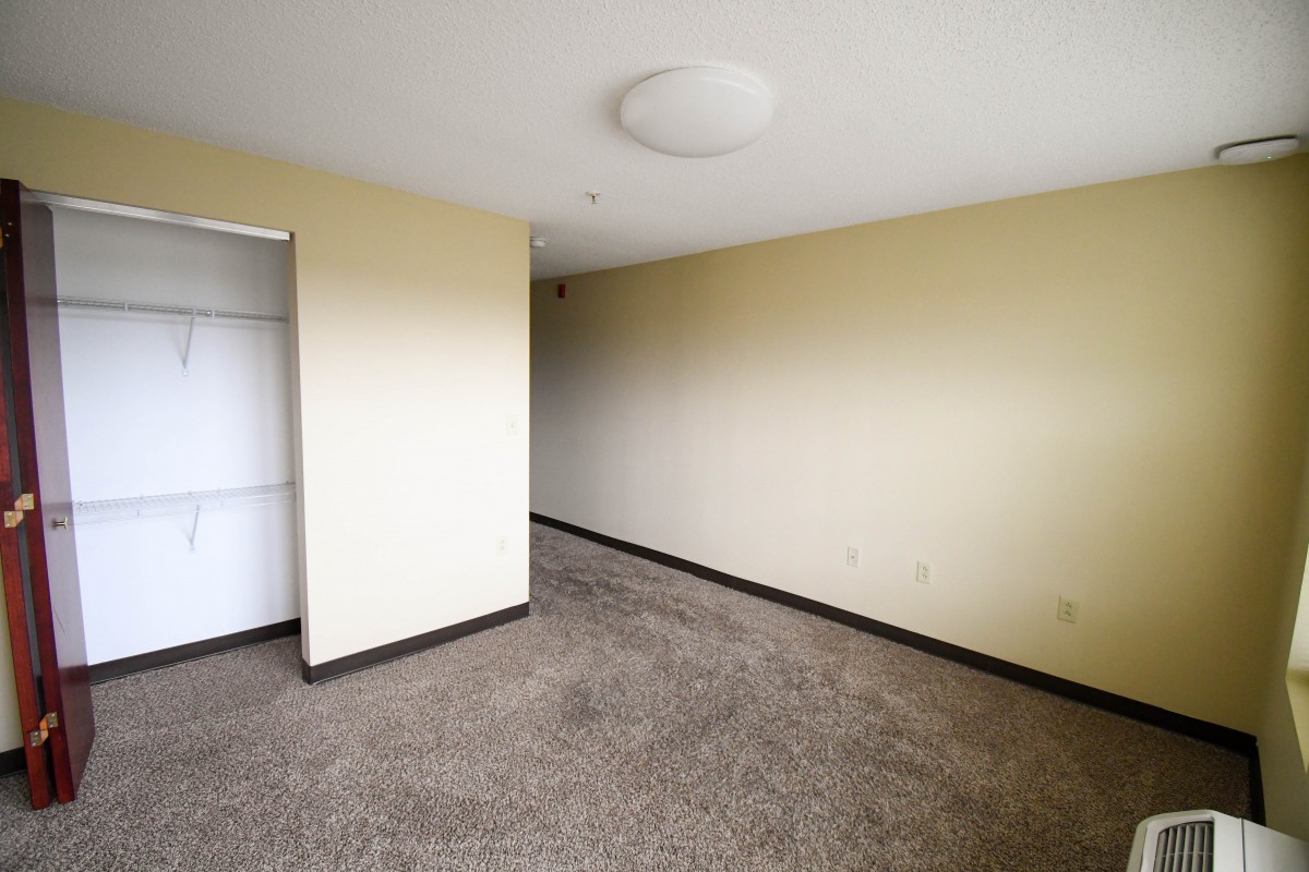 An empty room with carpeted flooring and neutral-colored walls.