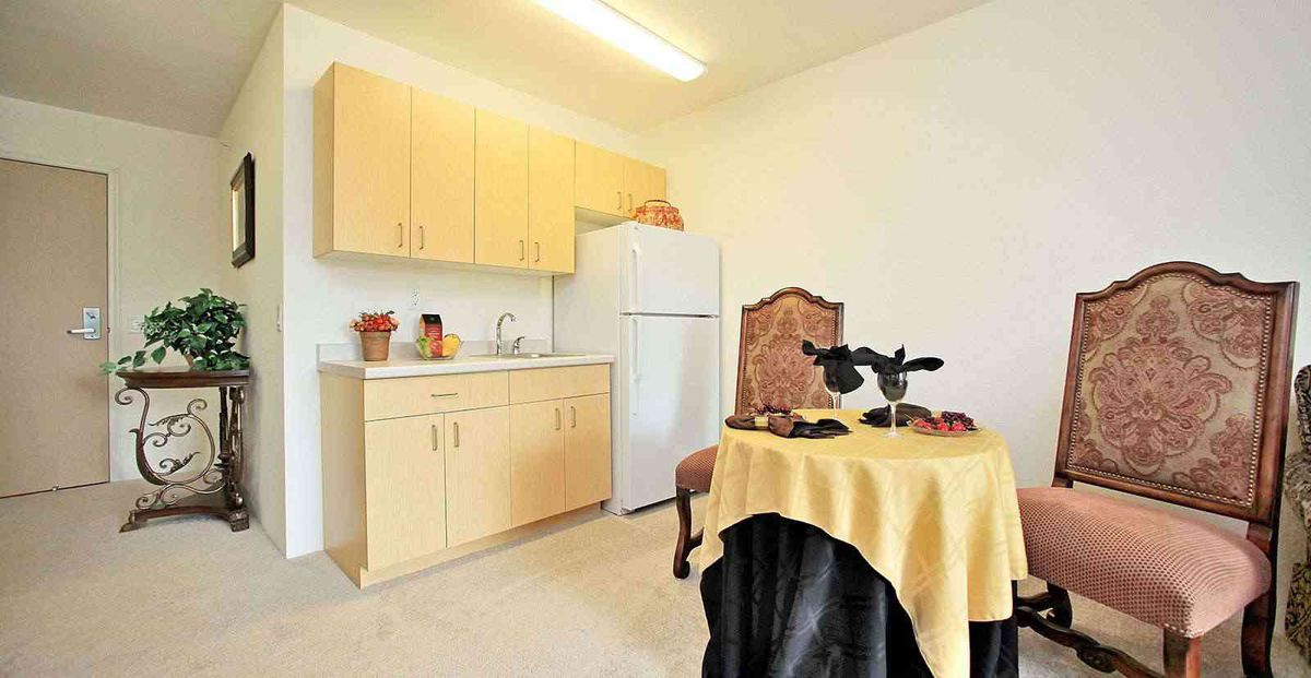 A small kitchen area with wooden cabinets, a white refrigerator, and a table set with a decorative centerpiece.