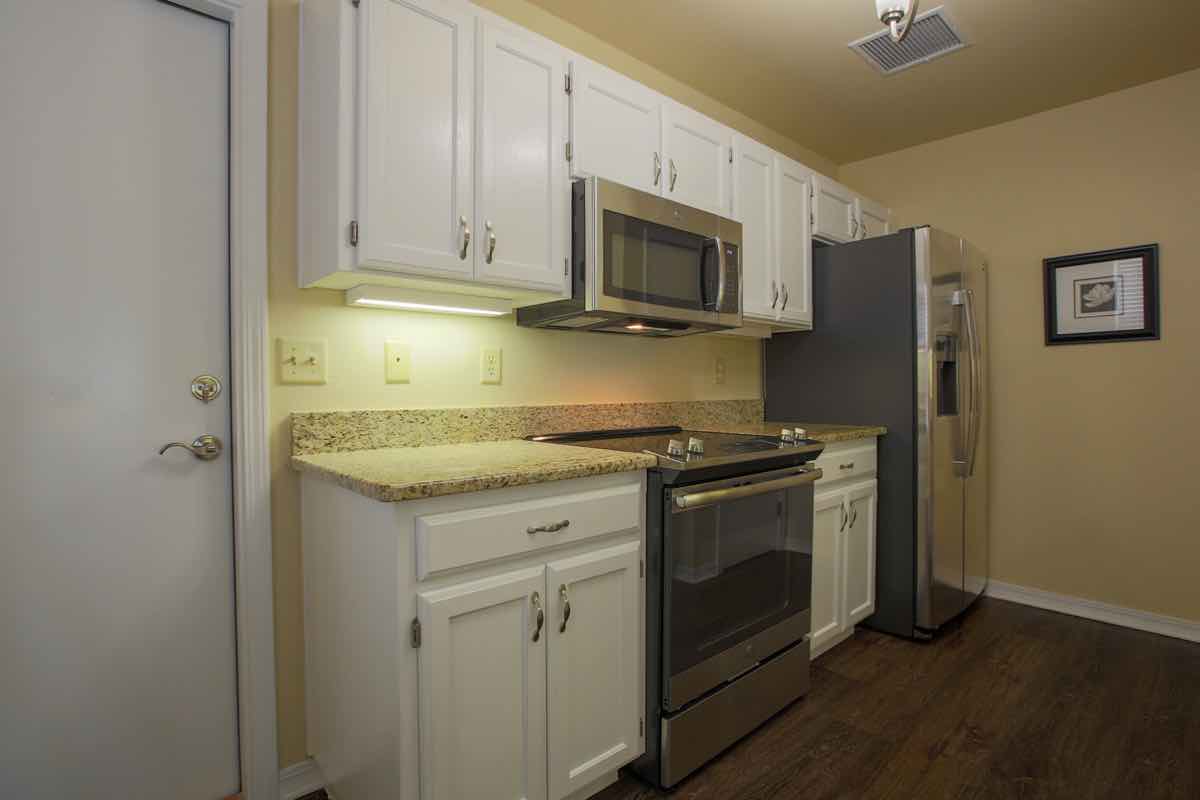 A modern kitchen with white cabinets and stainless steel appliances.
