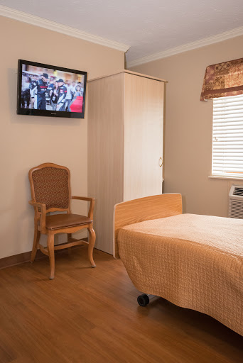 A cozy hospital room featuring a patient bed, television, and comfortable chair.