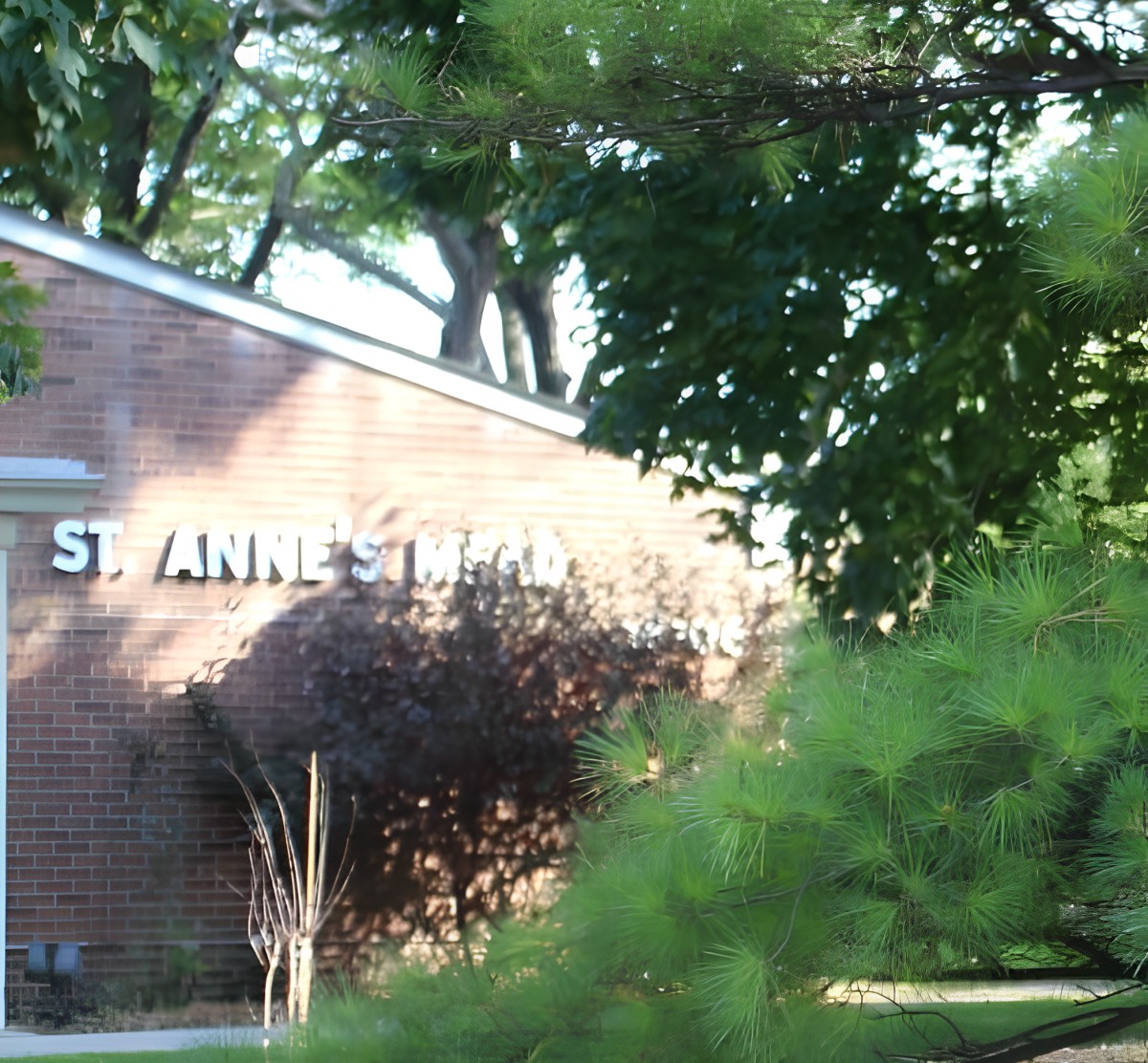 A brick building partially obscured by trees and greenery.