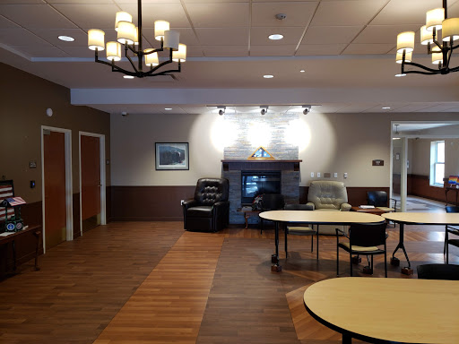 A spacious lobby area featuring tables, chairs, and a cozy fireplace.