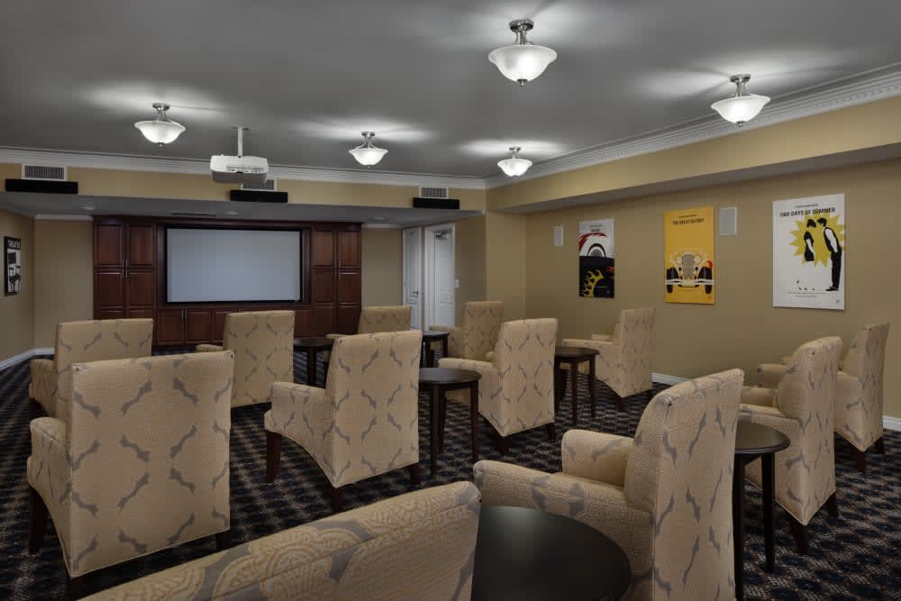 A conference room arranged with comfortable chairs and a projector screen, ready for a meeting or presentation.
