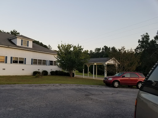A scenic view of a house with a gazebo and parked car during the evening.
