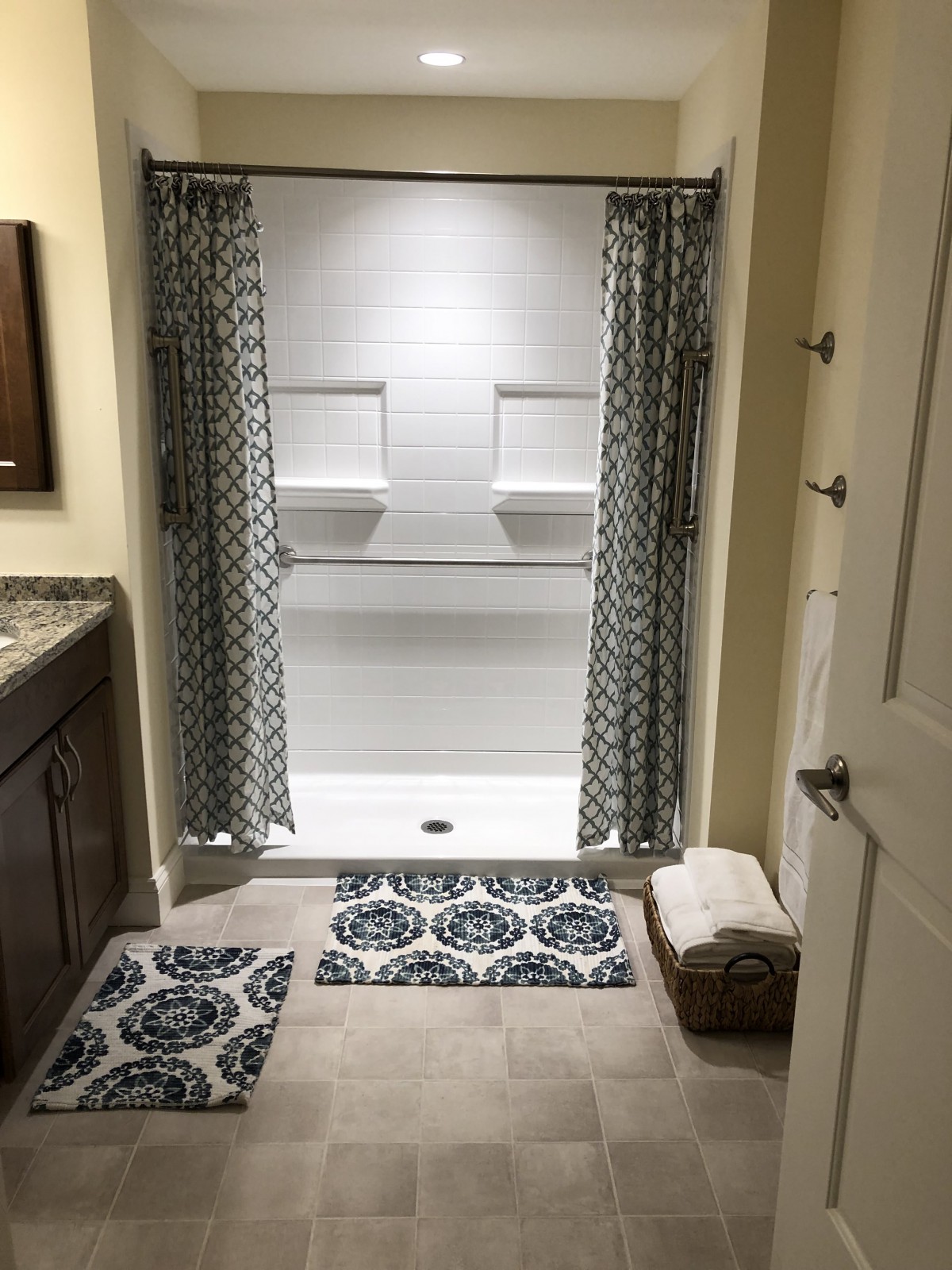 A neatly organized bathroom with a shower, patterned curtains, and matching rugs.