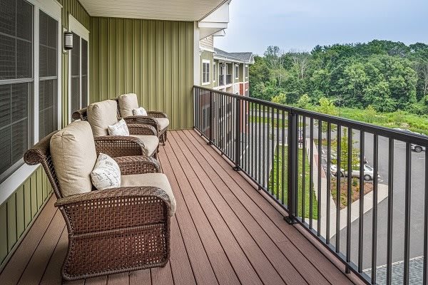 A cozy balcony with comfortable wicker chairs overlooking a green landscape.