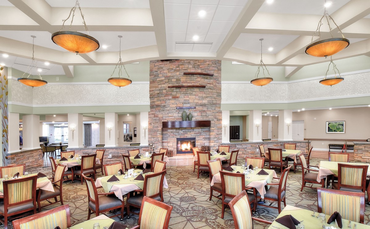A spacious dining area featuring modern decor with a central fireplace surrounded by neatly arranged tables and chairs.