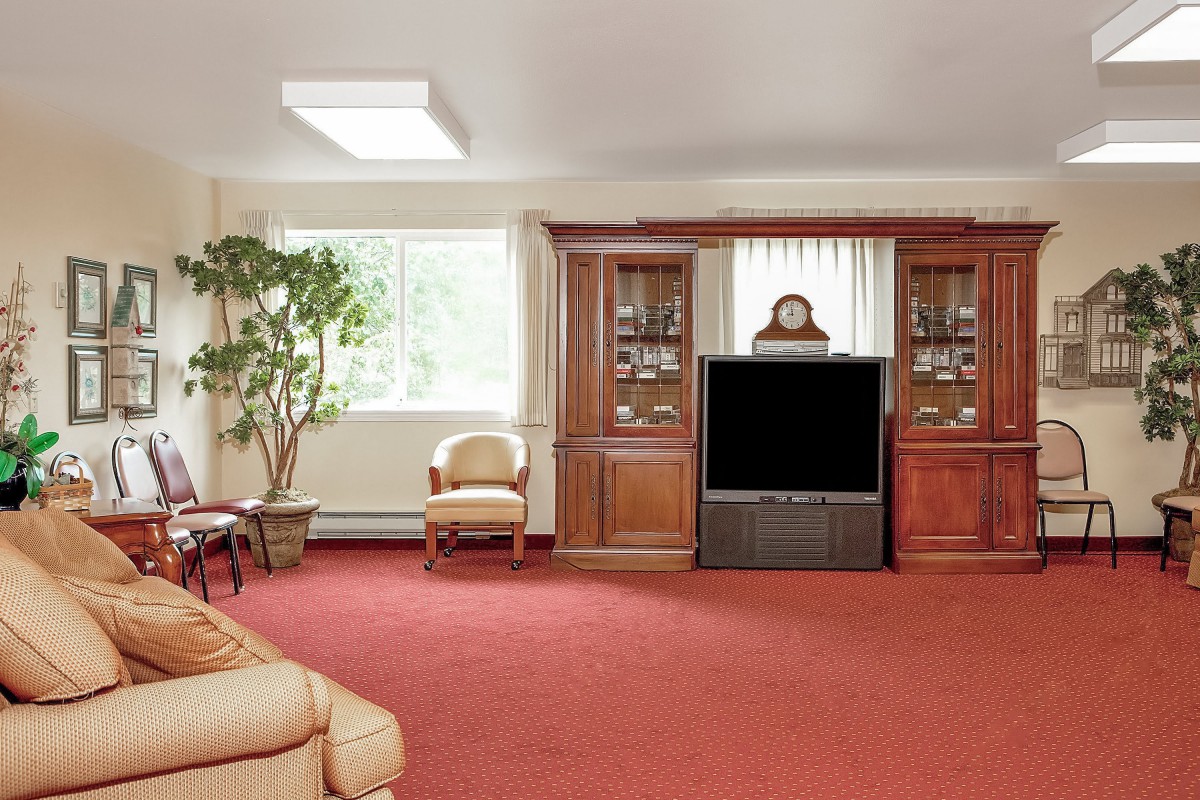 A cozy living room with a large TV, bookshelves, and comfortable seating.