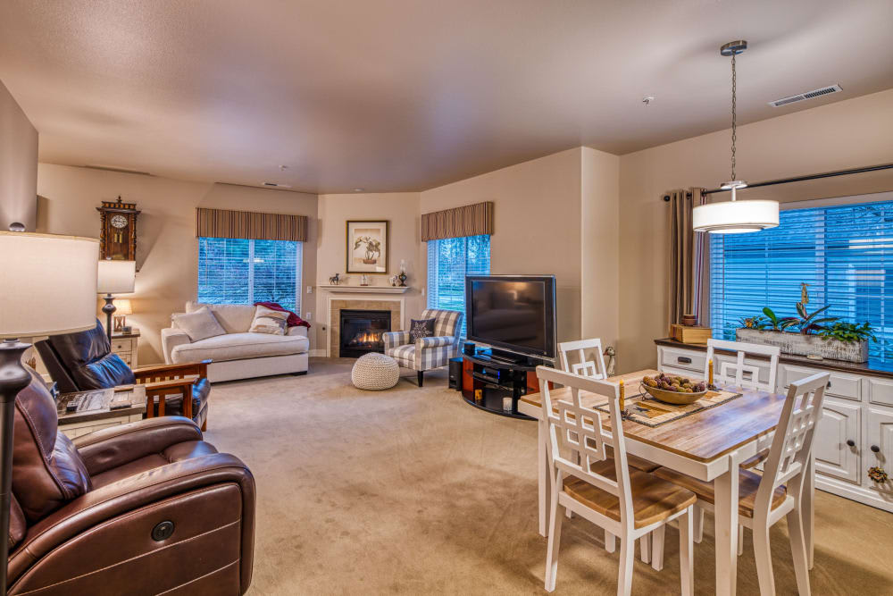 A cozy living and dining space featuring a sofa, fireplace, dining table, and a television.