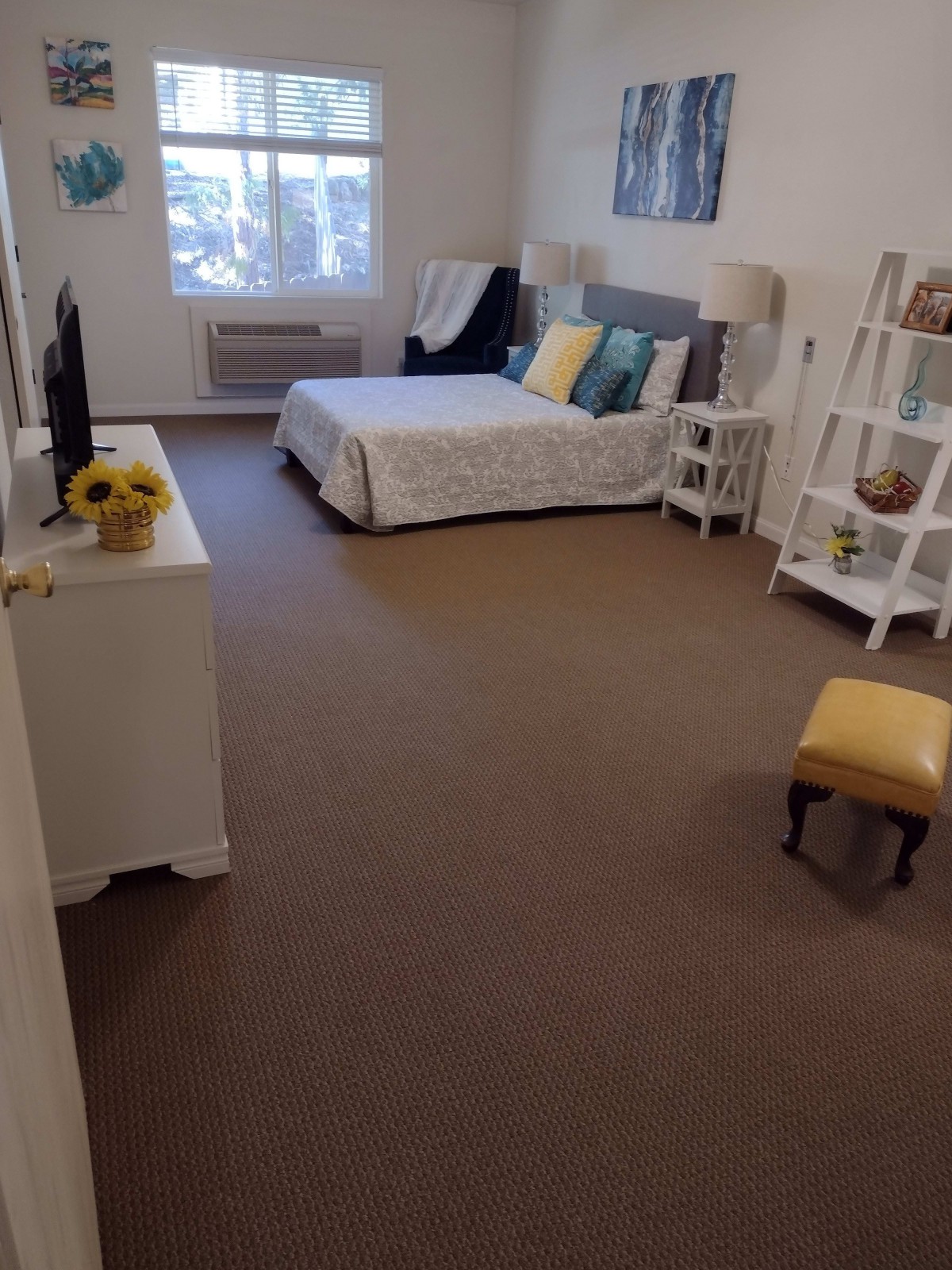 A cozy and well-decorated bedroom with a large bed, side tables, and a TV stand.