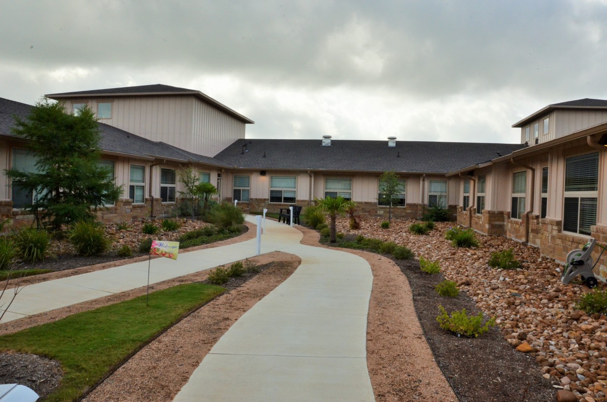 A modern building with a landscaped path under a cloudy sky.