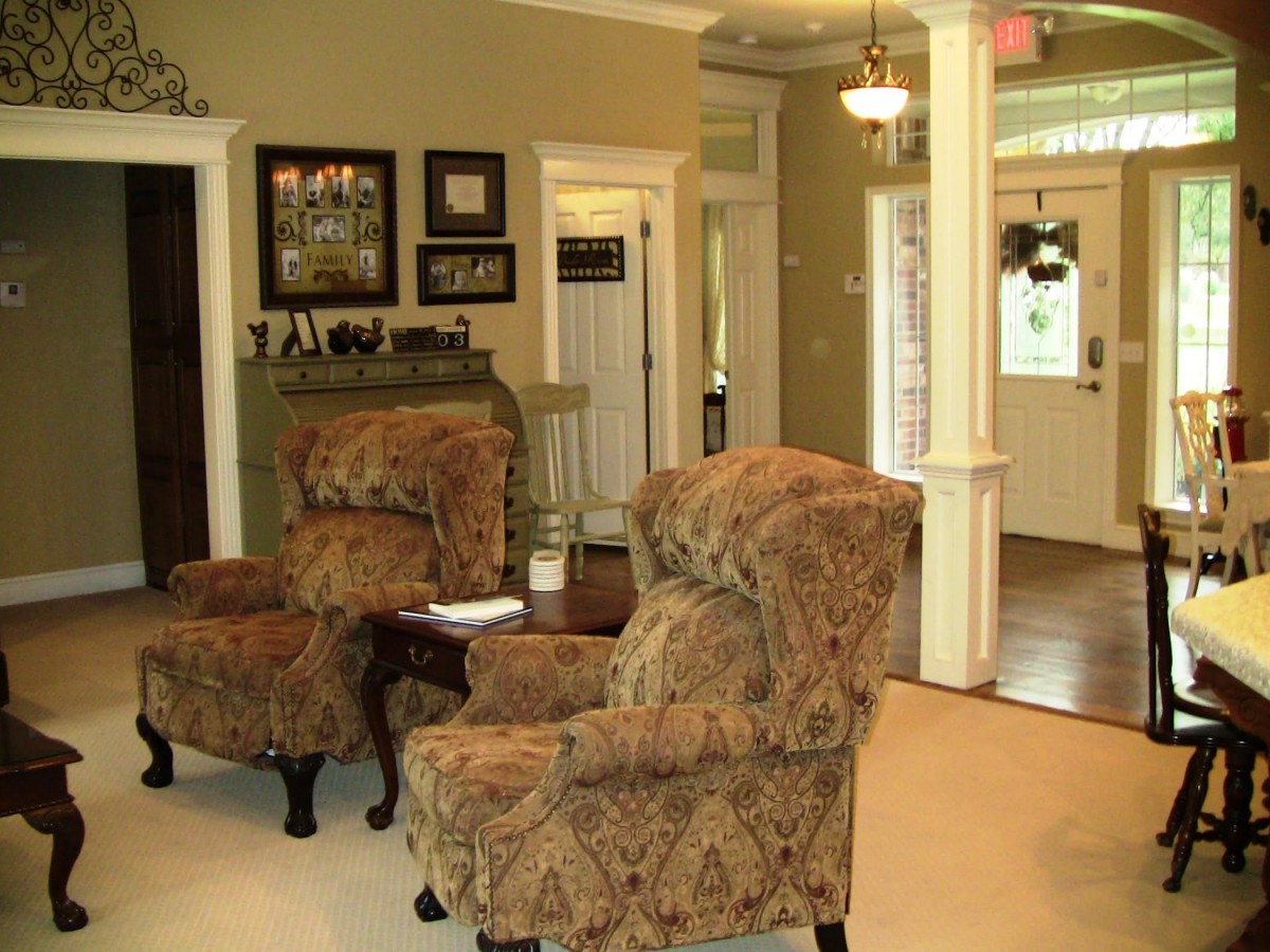 Traditional living room with armchairs, a fireplace, and framed pictures.