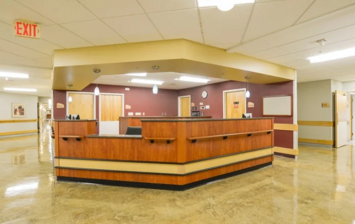 A spacious office reception area with a wooden desk and overhead lighting.