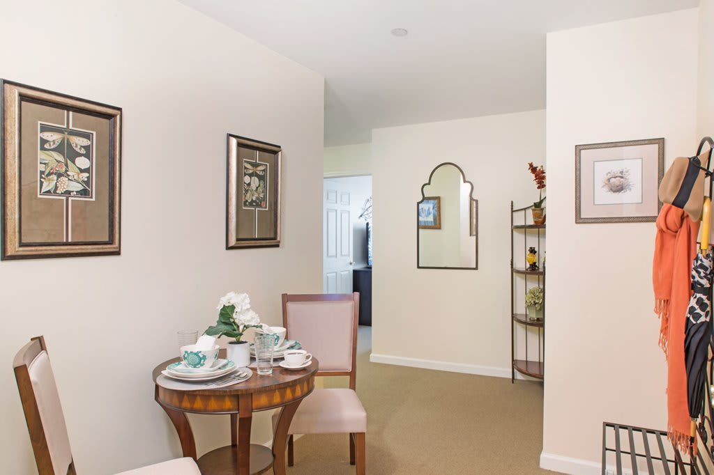 A cozy living room corner with a small round table and two chairs, decorated with elegant tea set and wall arts.