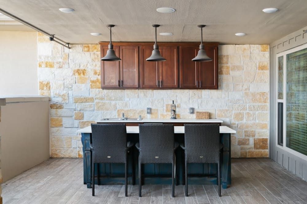 A modern kitchen with a central island, pendant lighting, and bar stools.
