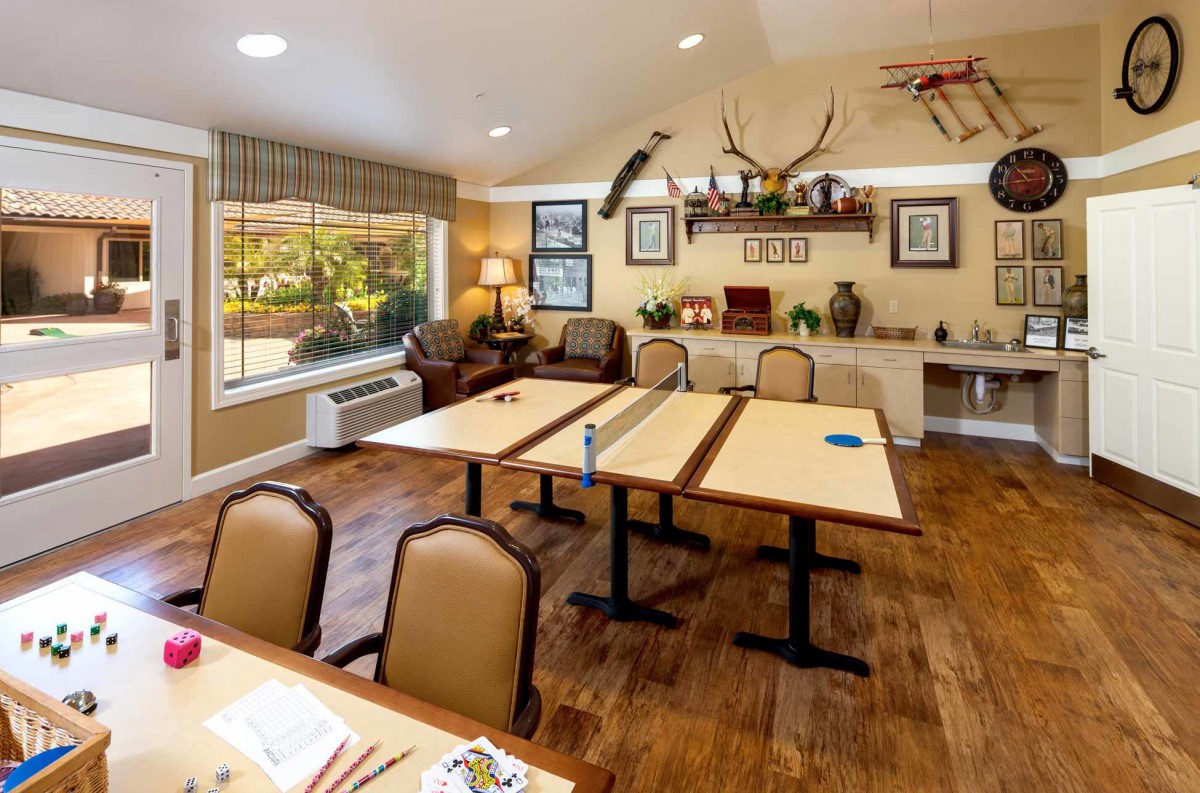 A well-lit meeting room with wooden flooring, featuring tables and chairs. The room is decorated with antlers, a model airplane, and framed pictures on the wall.