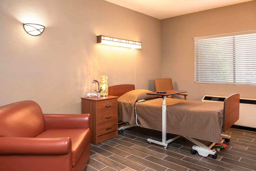 A hospital room with a bed, bedside table, and medical equipment.