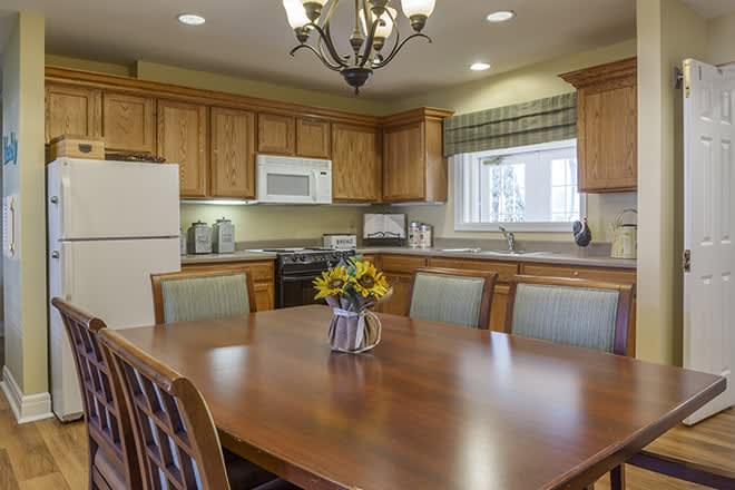 A cozy kitchen with wooden cabinets, a dining table, and modern appliances.