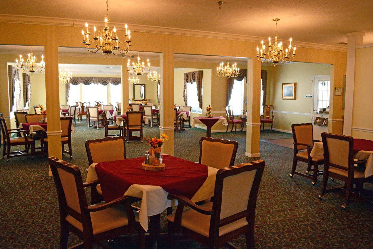 An elegant dining area with chandeliers and well-arranged tables in a warm, inviting atmosphere.