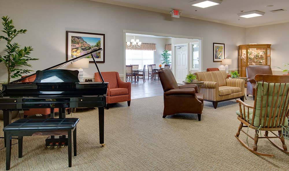 A spacious living room with a grand piano and comfortable seating arrangements.