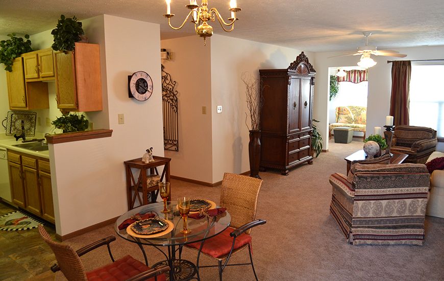 A cozy dining and living room area with a chandelier, table setting, and wooden furniture.