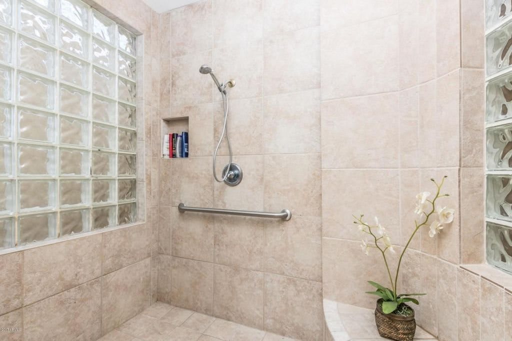 Modern bathroom shower with tiled walls and a glass block partition.