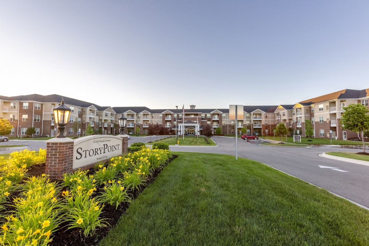 A well-landscaped residential apartment complex with visible signage at the entrance.