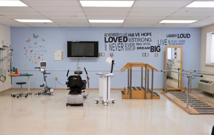 A well-equipped physical therapy room featuring various rehabilitation devices and motivational quotes on the wall.