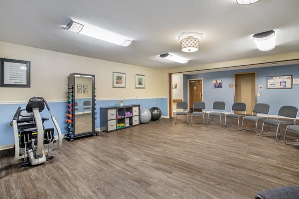 A spacious fitness room with exercise equipment and seating.