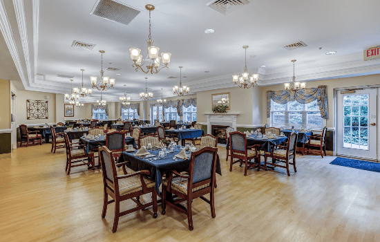 An elegant dining area with neatly arranged tables and chairs under ornate chandeliers.