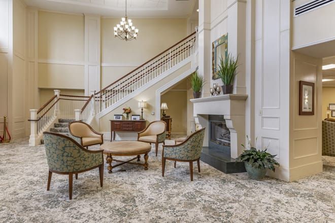 A luxurious lobby with elegant furniture, a grand staircase, and a cozy fireplace.