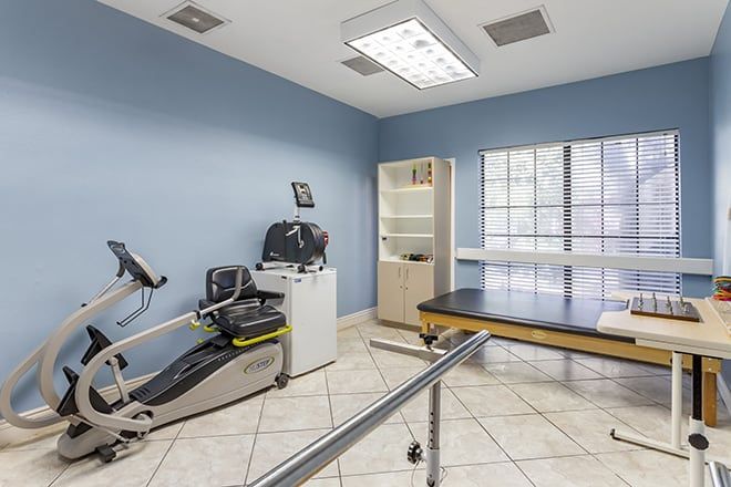 A well-equipped therapy room with exercise machines and a treatment table.