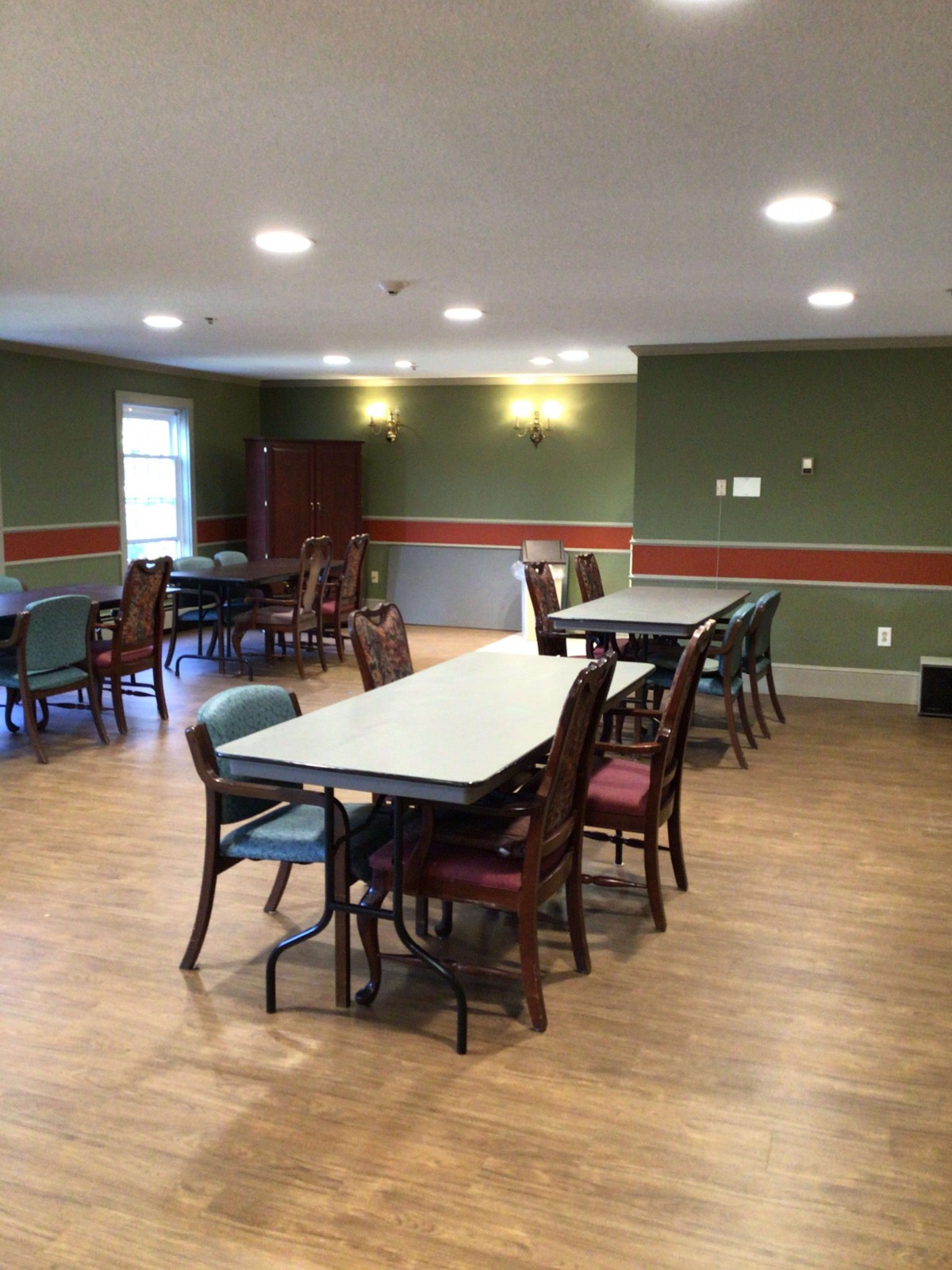 An empty community dining area with multiple tables and chairs arranged neatly.