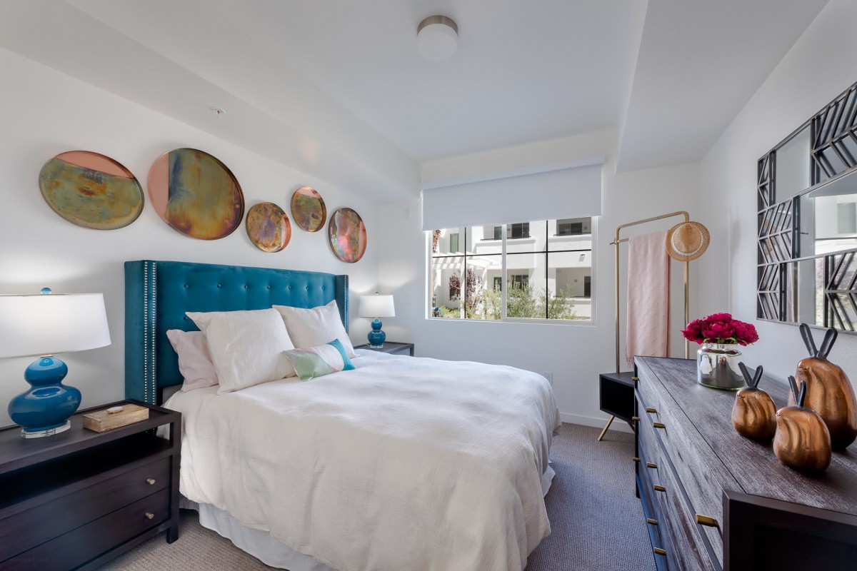 A modern bedroom with stylish decor, featuring a teal headboard and circular wall art.