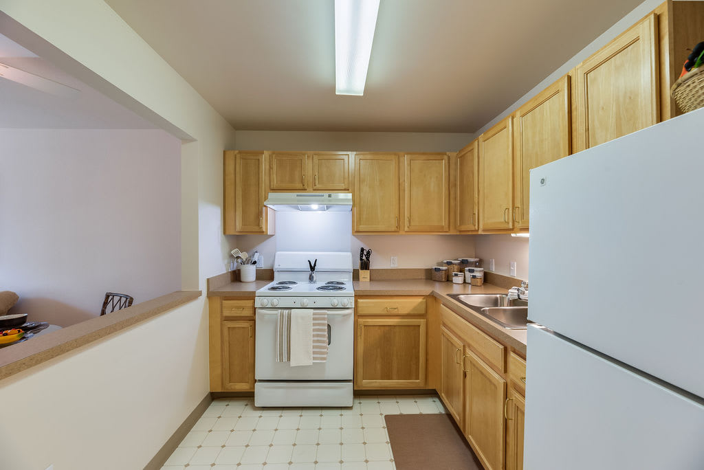A cozy kitchen with wooden cabinets, a stove, refrigerator, and ample countertop space.