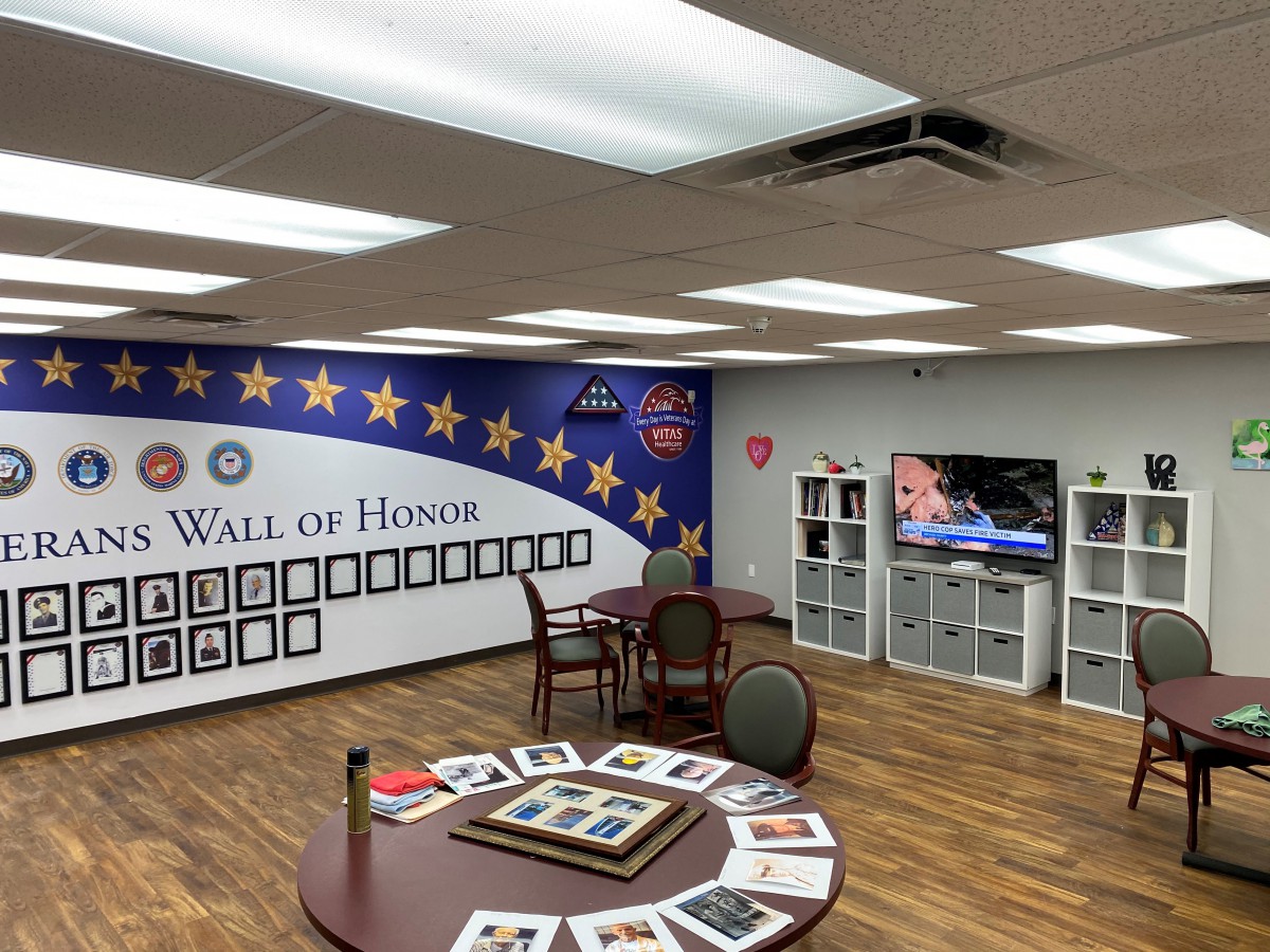 A commemorative Wall of Honor featuring military memorabilia and photographs in a well-lit room.