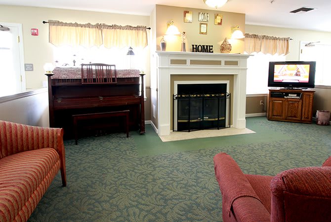 A cozy living room featuring a fireplace and a piano.