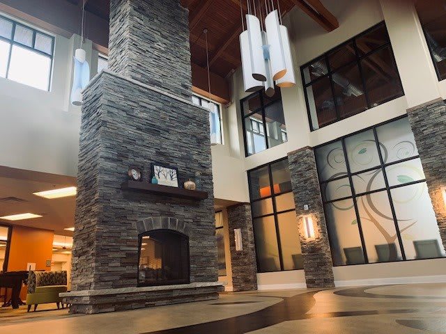 A modern lobby featuring a large stone fireplace and contemporary chandeliers.