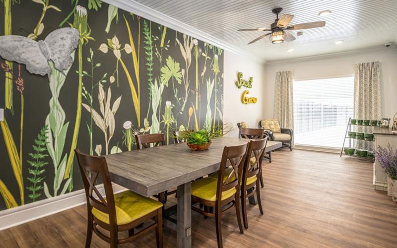 A stylish dining room with a botanical wallpaper and wooden furniture.