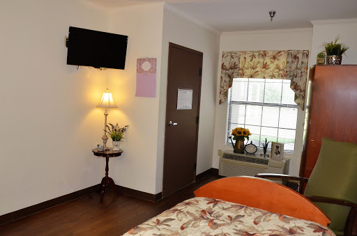 A cozy and well-decorated room featuring a TV, a bedside lamp, and floral curtains by the window.