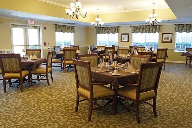 An elegant dining room setup with neatly arranged tables and chairs under chandeliers.