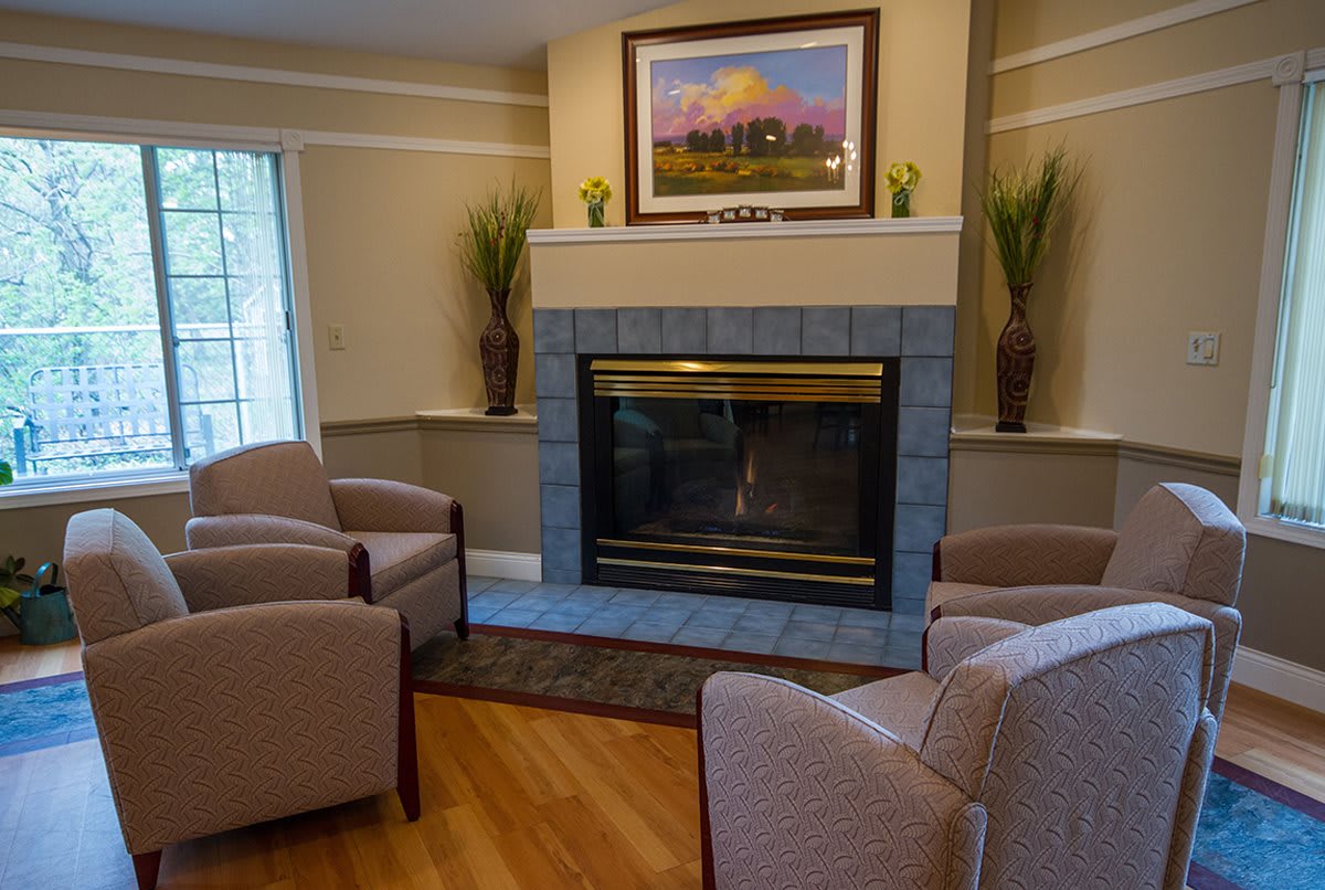 A cozy living room with a fireplace surrounded by comfortable chairs and tasteful decor.