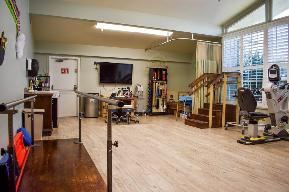 A spacious physical therapy room equipped with various rehabilitation tools and exercise equipment.