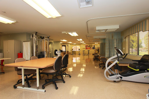 A spacious rehabilitation therapy room equipped with exercise machines and workstations.
