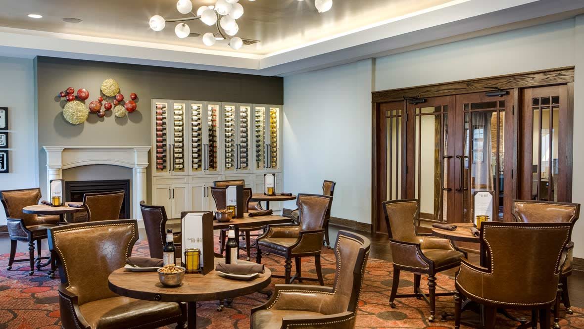 An elegant restaurant dining room with a wine display and cozy seating arrangement.