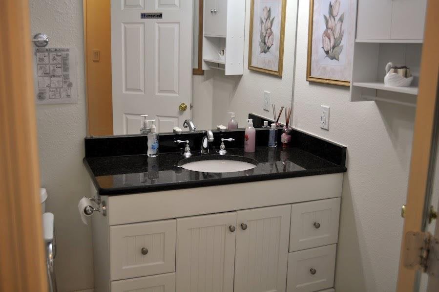 A bathroom vanity with a black countertop, sink, and mirror, adorned with decorative elements.