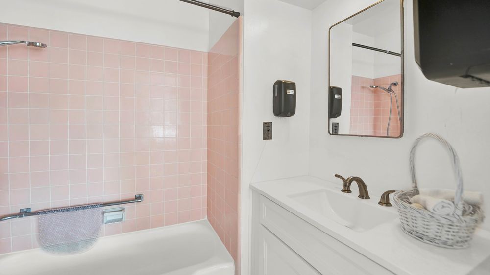 A modern bathroom featuring pink tiles with a bathtub and sleek fixtures.