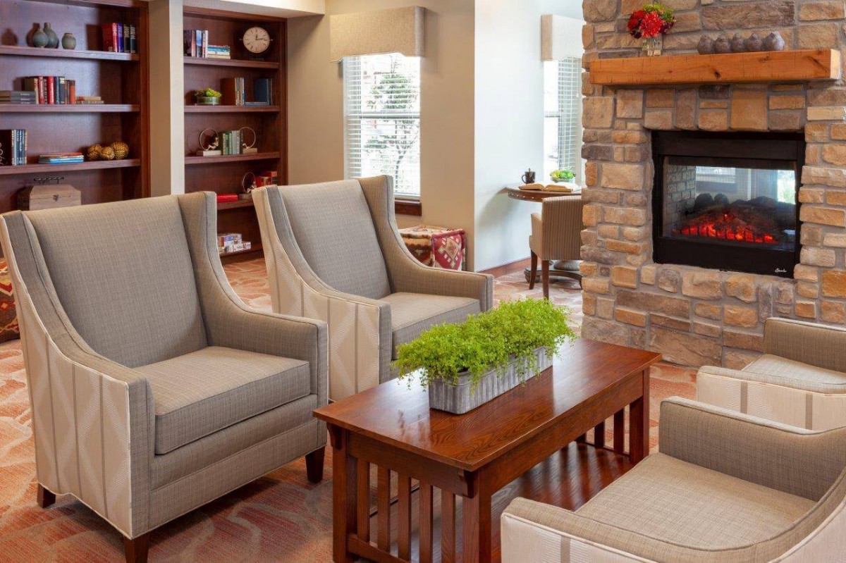 A cozy living room with armchairs, a stone fireplace, and a wooden coffee table adorned with a plant.
